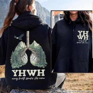 May include: Black hoodie featuring a graphic of lungs formed by trees, with an eagle and the text "YHWH every breath speaks His name." The front of the hoodie displays "YH WH every breath speaks His name."