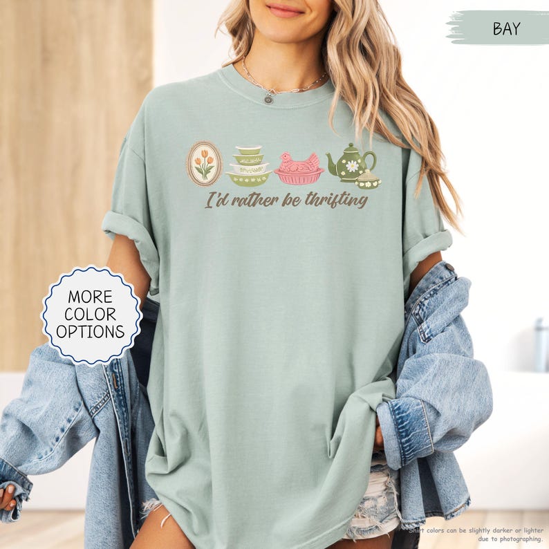 Pu&ograve; includere: T-shirt verde chiaro con la scritta "I'd rather be thrifting" e illustrazioni di utensili da cucina vintage. La maglietta presenta una grafica rotonda con le parole "More Color Options". La maglietta &egrave; di vestibilit&agrave; ampia.