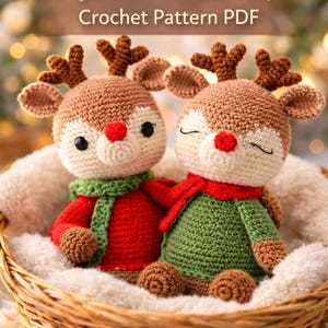 May include: Two amigurumi reindeer dolls in a woven basket. The reindeer have brown bodies, cream-colored faces, and red noses. One wears a red sweater and green scarf, the other a green sweater and red scarf. The text reads "Amigurumi Reindeer Couple Crochet Pattern PDF".