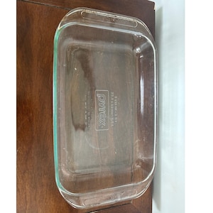 Op de afbeelding: Een rechthoekige Pyrex ovenschaal van helder glas met afgeronde hoeken en handgrepen. Het Pyrex-logo en de afmetingen zijn zichtbaar. De schaal meet 22.86 x 33.02 cm. Perfect voor bakken en koken.