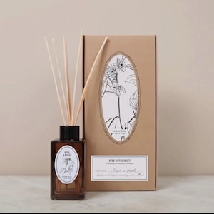 May include: A brown glass reed diffuser bottle with wooden reeds and a matching box. The bottle has a label that reads "Basil & Neroli" with a floral illustration. The box features an oval design with a floral illustration and the text "Reed Diffuser Set".