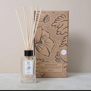 May include: A brown cardboard box with a floral design and the text "Reed Diffuser Set" and "Norfolk" on the front. The box contains a clear glass bottle with a black lid and wooden sticks. The bottle is labelled "Coastal Walks Reed Diffuser" and "Norfolk".