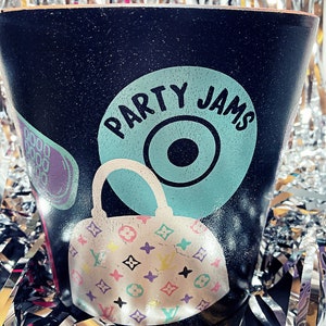 May include: A black planter with a blue and white circle that says "Party Jams" and a white handbag with a black, white, and pink pattern.