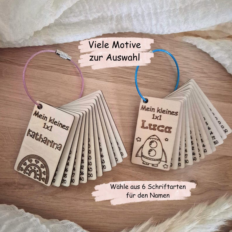 May include: Two sets of rectangular wooden cards on metal rings. The left set features a rainbow design and the name Katharina, with text reading Mein kleines 1x1. The right set features a rocket design and the name Luca, with text reading Mein kleines 1x1.
