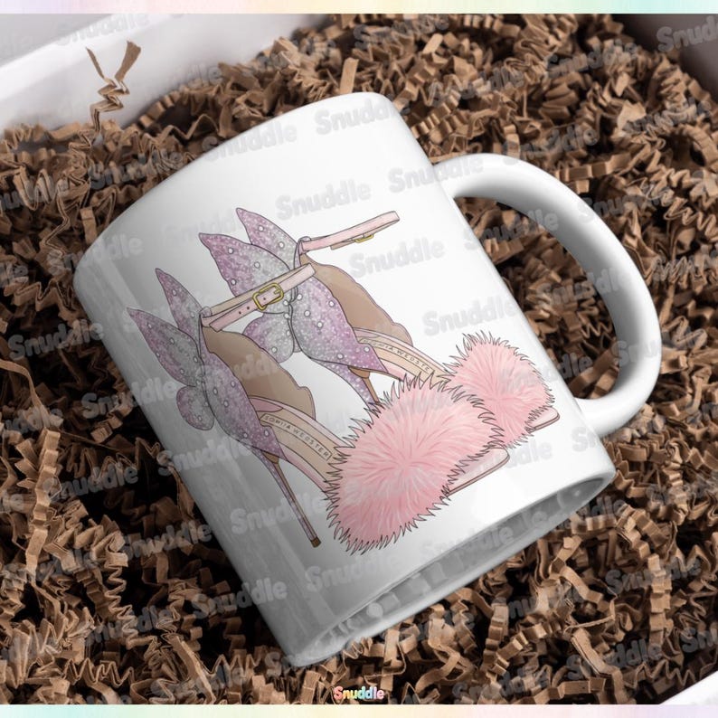 May include: White ceramic mug featuring a whimsical illustration of high-heeled shoes. The shoes are adorned with pink fur, light pink straps, and a delicate butterfly design. The mug has a curved handle and is set against a brown background.