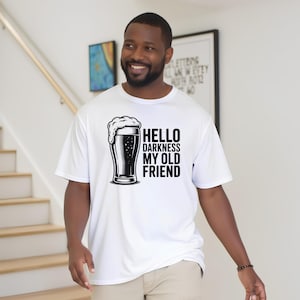 May include: White t-shirt with a black and white graphic of a beer glass and the text "Hello Darkness My Old Friend". The shirt is made of a lightweight material.