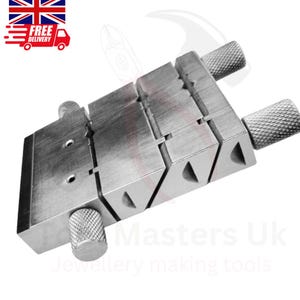 May include: A silver jewellery making tool with adjustable sections and knurled knobs. The tool has a rectangular shape with angled grooves and is designed for holding and shaping materials. The image also includes a Union Jack flag and a delivery truck icon.