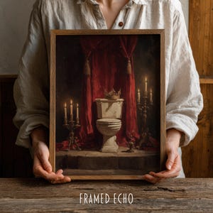 Op de afbeelding: Ingelijste kunst met een toilet met een kroon, tegen een rode gordijnachtergrond. Brandende kaarsen en kandelaars flankeren het toilet, wat een dramatische, vintage esthetiek creëert. De tekst "FRAMED ECHO" staat onderaan.