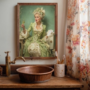 Op de afbeelding: Een ingelijste prent van een vrouw in een groene jurk die een glas champagne vasthoudt. De prent wordt weergegeven boven een koperen wastafel en kraan. Rechts is een bloemengordijn zichtbaar.