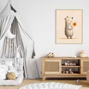 May include: A framed illustration of a smiling bear holding a sunflower. The artwork has a light beige background and is displayed in a child's bedroom. The room also features a gray canopy bed, a wooden cabinet, and decorative toys.