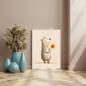May include: A framed art print featuring a cartoon bear holding a sunflower. The bear is light gray with a smiling face. The sunflower is yellow with a brown center. The background is a light beige color.
