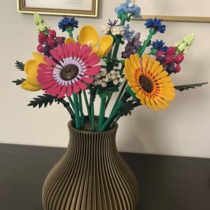 May include: A colorful bouquet of flowers in a brown vase. The flowers include pink, yellow, and blue blooms with green stems. The vase has a ribbed design.