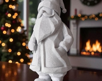 Puede incluir: Una figura de Papá Noel de color gris claro moteado con un diseño geométrico facetado. La figura presenta un gorro puntiagudo con un pompón, una barba larga, un bigote y un abrigo largo con las manos en los bolsillos, de pie.