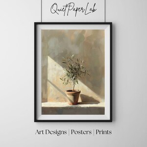 May include: Framed art print featuring a potted olive tree in a terracotta pot, set against a neutral-toned wall. The artwork is illuminated by a beam of sunlight, creating a contrast of light and shadow. The text "Quiet Paper Lab" is at the top.