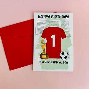 Peut inclure: Une carte d'anniversaire rouge et blanche avec un maillot de football, un trophée et un ballon de football. La carte dit "Joyeux anniversaire à un fils très spécial".