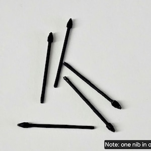 May include: Five black stylus replacement nibs arranged in a scattered pattern. Each nib features a slender, cylindrical body with a pointed tip at one end. The text "Note: one nib in order" is printed in white on a black rectangular background.