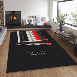 Puede incluir: Alfombra negra y roja con un diseño de rayas de carreras blancas. La alfombra presenta una silueta de un coche de carreras McLaren MP4/14.