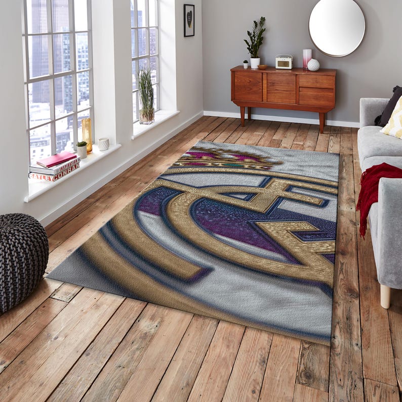 May include: A rectangular area rug featuring a large, centered emblem with a gold crown at the top. The design incorporates a prominent gold letter C intertwined with a gold letter F, set against a textured background of deep purple and white.