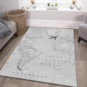 Könnte beinhalten: Ein grauer und weißer Weltkarten-Teppich mit einer kleinen Flugzeuggrafik in der Mitte. Der Teppich trägt die Aufschriften "South Atlantic Ocean" und "Antarctica".