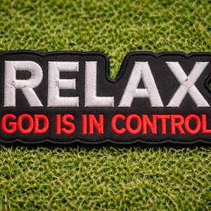 May include: Black embroidered patch with the words "RELAX GOD IS IN CONTROL" in white and red thread. The patch has a black border and is set against a green, textured background.