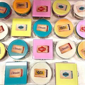 Puede incluir: Un conjunto de 10 posavasos redondos y cuadrados de colores con varios diseños. Cada posavasos presenta un gráfico diferente de una caja de cerillas con un nombre único impreso en él. Los nombres incluyen "Library", "Volta", "Funky's" y "Boure".