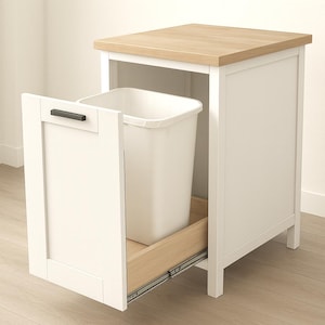 Könnte beinhalten: Ein weißer Mülleimer-Schrank aus Holz mit einer hellen Holzplatte und einer Ausziehtür. Der Schrank hat eine rechteckige Form und einen schwarzen Griff. Im Inneren befindet sich ein weißer Kunststoff-Mülleimer.
