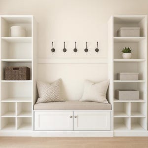 Puede incluir: Una unidad de almacenamiento blanca empotrada con estantes, un banco y un armario. La unidad tiene dos estanterías altas a cada lado, con un banco y un armario en el centro. Hay ganchos decorativos montados encima del banco.