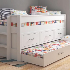 Puede incluir: Cama litera blanca con cama nido extraíble. La cama cuenta con una escalera incorporada, tres cajones y detalles estampados coloridos en el cabecero y la cama nido. Las almohadas con varios patrones están en la litera superior y en la cama nido.