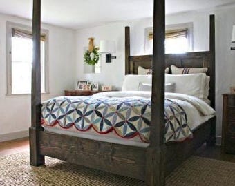 May include: A dark wood four-poster bed with a patterned quilt in a bedroom setting. The quilt features a floral design in blue, white, and red. The room has white walls, a rug, and a dresser.