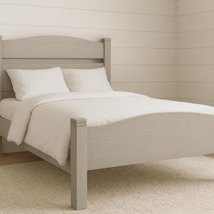 May include: A light gray wooden bed frame with a curved headboard and footboard. The bed is made up with white bedding and pillows. The bed is on a light beige rug.