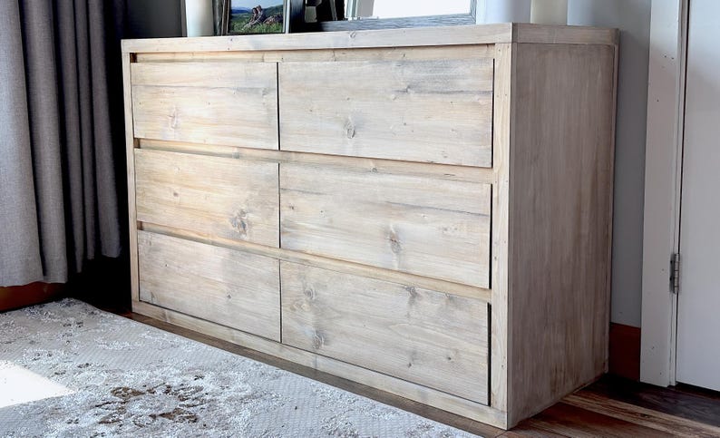 May include: A light-colored wooden dresser with six drawers. The dresser is made of light-colored wood and has a simple, modern design. The drawers are arranged in two columns of three.