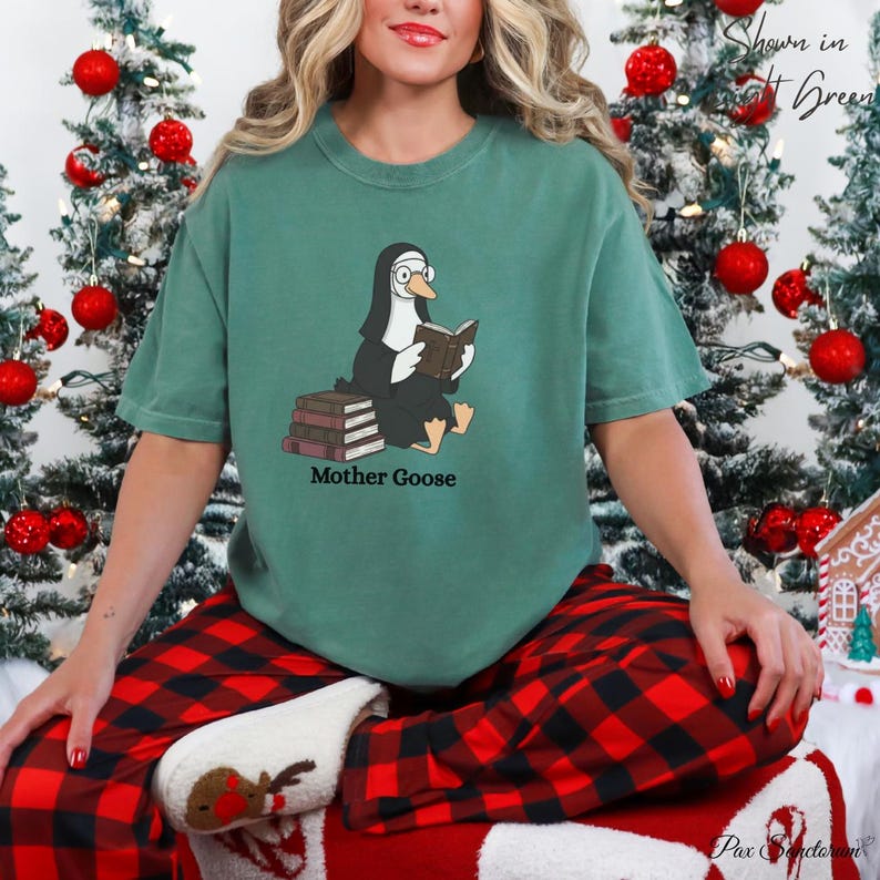 K&ouml;nnte beinhalten: Ein gr&uuml;nes T-Shirt mit einer Cartoon-Gans in Nonnentracht, die ein Buch liest, mit dem Text "Mother Goose" darunter. Die Gans sitzt auf B&uuml;chern. Die Person tr&auml;gt eine rot-schwarz karierte Pyjamahose.