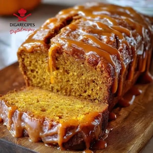 May include: A sliced loaf of pumpkin bread with caramel drizzle on a wooden cutting board. The bread is golden brown with a moist texture, and the caramel is a rich, glossy brown. The text "DIGARECIPES Digital recipes" is in the upper left corner.