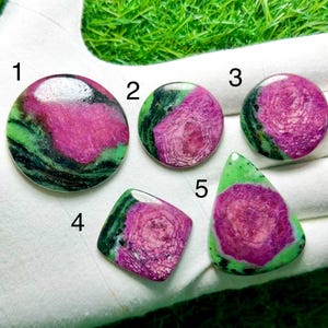 Può includere: Cinque pietre preziose cabochon lucidate numerate da 1 a 5, caratterizzate da un mix di motivi magenta-rosa vivaci e verde intenso. Le pietre includono tre forme circolari, una forma quadrata e una forma a goccia, tutte con superfici lisce.
