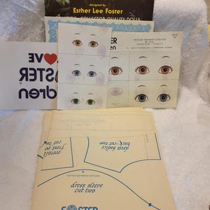 May include: A collection of sewing patterns and iron-on transfer sheets for soft sculpture dolls by Esther Lee Foster. The set includes printed paper templates for doll clothing, sheets of illustrated eyes in various colors, and instructional booklets.