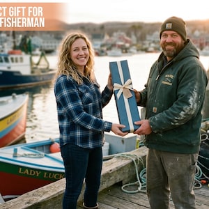Pu&ograve; includere: Una lunga scatola regalo rettangolare avvolta in carta blu scuro con un nastro color crema e una piccola etichetta. La scatola &egrave; tenuta da due persone su un molo di legno. Il testo "PERFECT GIFT FOR EVERY FISHERMAN" &egrave; visibile nella parte superiore.
