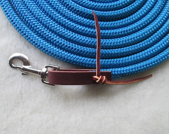 May include: A bright blue braided rope leash coiled in a circle. The leash features a silver-toned metal swivel snap hook attached to a dark brown leather connector piece, which is secured with a thin leather cord tied in a simple knot.