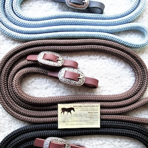 May include: Three braided leather reins with silver conchos and brown leather straps. The reins are in blue, brown, and black. The image also includes a business card for Rose Lodge Equine Supply LLC.