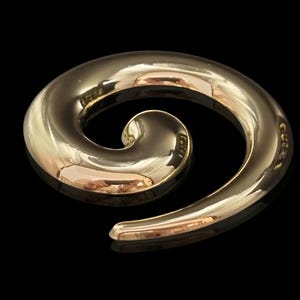 Może przedstawiać: Polerowany, złoty przedmiot w kształcie spirali. Gładki, zakrzywiony kształt odbija światło, tworząc refleksy i cienie. Spirala jest jednoczęściowa, z zaokrąglonym, zwężającym się końcem. Obiekt umieszczony na czarnym tle.