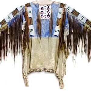 Puede incluir: Una túnica de estilo nativo americano con una combinación de colores azul claro y beige. La túnica presenta intrincados abalorios en blanco, marrón y azul, junto con largas y oscuras franjas marrones a lo largo de las mangas y el dobladillo.