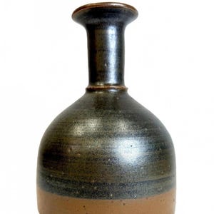 May include: A handcrafted ceramic vase with a dark, mottled glaze. The vase features a rounded body and a slender neck, with a brown base and rim. The vase is approximately 20 cm tall.