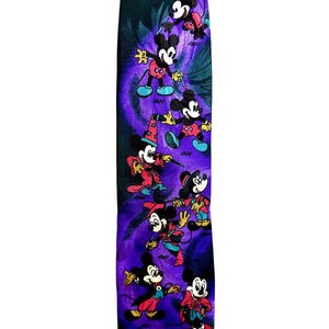 Puede incluir: Una corbata morada oscura con un patrón repetido de Mickey Mouse con varios atuendos. La corbata tiene un fondo morado y verde azulado. Mickey lleva trajes rojos, negros y azules.