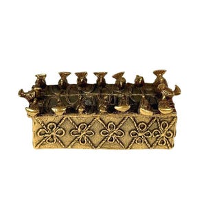 May include: A rectangular brass box featuring a textured surface with a repeating diamond pattern and four-petaled flower motifs. The lid is adorned with a series of small, stylized bird figures arranged along the top edges and corners.