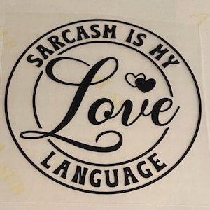 Puede incluir: Un diseño circular con la frase "Sarcasm is my Love Language" en letras negras. La palabra "Love" está en cursiva, con dos corazones encima. El diseño está sobre un fondo blanco.