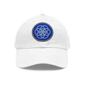 May include: White baseball cap with a circular patch featuring a blue and white geometric design. The patch is outlined in gray and is centered on the front of the cap. The cap has a curved brim and an adjustable strap.