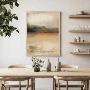 May include: Abstract landscape art print in a light wood frame. The artwork features a muted color palette with beige, black, and orange hues. The painting depicts a minimalist landscape with a horizon line and a textured appearance.