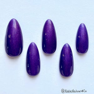 May include: Five purple oval-shaped press-on nails with a shimmery finish.