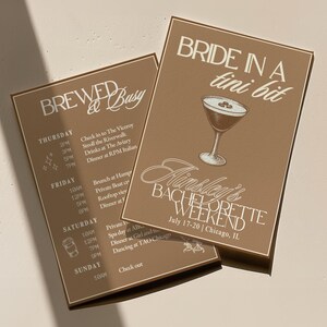 Può includere: Due biglietti per eventi color beige con testo bianco. Un biglietto recita "BREWED & Busy" con un programma. L'altro dice "BRIDE IN A tini bit" con una grafica di martini e i dettagli di "Ainsley's BACHELORETTE WEEKEND".