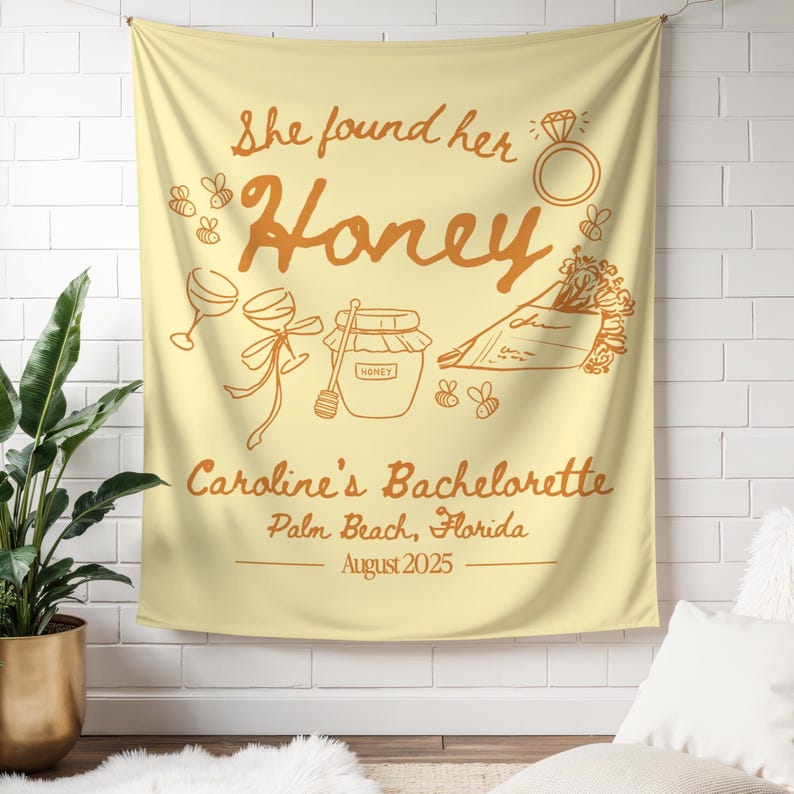 May include: A light yellow tapestry with brown text and illustrations. The text reads "She found her Honey" with a ring, bees, and other illustrations. Below, it says "Caroline's Bachelorette, Palm Beach, Florida, August 2025."