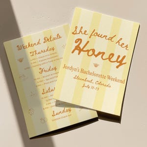 Op de afbeelding: Twee geel gestreepte evenementkaarten met oranje tekst. Eén kaart leest "She found her Honey" en details voor een vrijgezellenweekend in Steamboat, Colorado. De andere kaart geeft de weekenddetails weer.